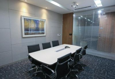Professional meeting room with a white conference table and black leather chairs.