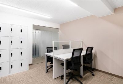 Open-plan workspace with white desks, privacy dividers, and storage lockers.