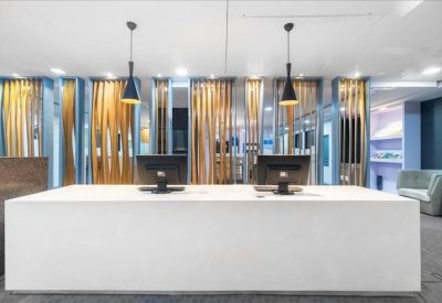 Sleek white reception desk with modern pendant lights and a wood-slat backdrop.
