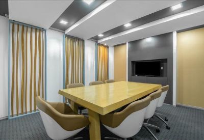 Spacious boardroom with a large light wood table and integrated media screen.