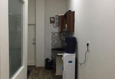 Compact office kitchen and corridor featuring a water cooler and wooden flooring.