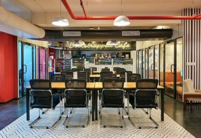 Modern coworking space with black mesh chairs and an on-site cafe in the background.