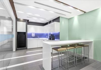 Modern communal kitchen and break area with a high white breakfast bar and stools.