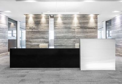 Professional reception area with a black and white front desk and stone-textured walls.