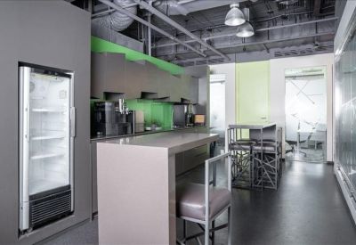 Modern communal kitchen and breakout area with a breakfast bar and green accents.