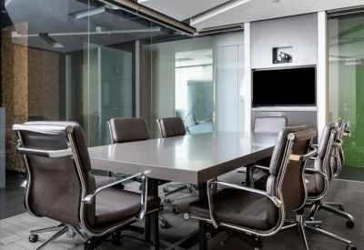 Spacious boardroom with a large grey table, ergonomic leather chairs, and architectural ceiling details.