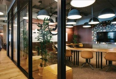 Modern hallway featuring glass-walled offices and a large conference table.