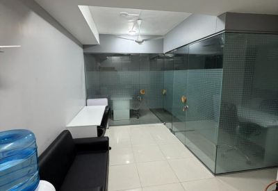 Communal breakout area with a black sofa, water dispenser, and glass-walled offices.