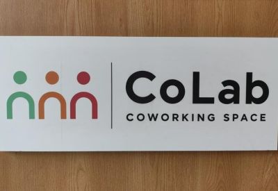 Branded signage for CoLab Coworking Space on a light wood wall.