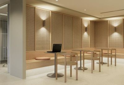 Breakout area featuring small cafe tables, a wooden bench seat, and warm wall sconce lighting.