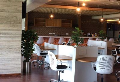 Modern coworking area with white ergonomic chairs and built-in desk pods.
