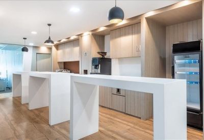Contemporary office breakout area with high white counters and a kitchen station.