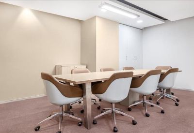 Professional boardroom with a long wooden table and stylish white and tan chairs.