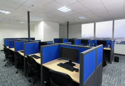 Blue-walled cubicle workstations with computer monitors and office chairs.