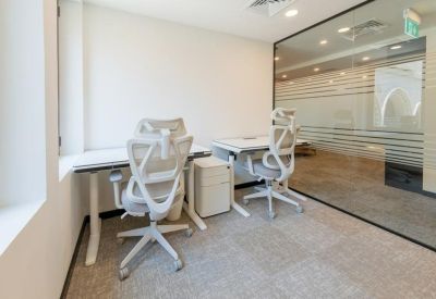 Two-person workspace featuring height-adjustable desks and view through a glass wall.