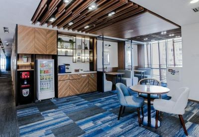 Communal break area featuring a coffee station, chevron wood cabinetry, and blue patterned carpet.