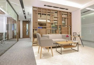 Bright reception area with a decorative wooden partition and plush grey seating.