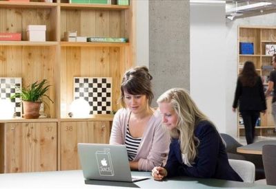 Two women collaborating at a table with a laptop.