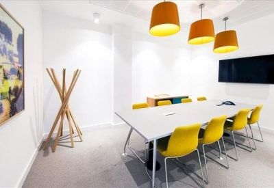 Modern meeting room with yellow chairs and large screen.