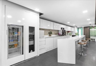 Bright white communal kitchen and break area with bar stool seating.