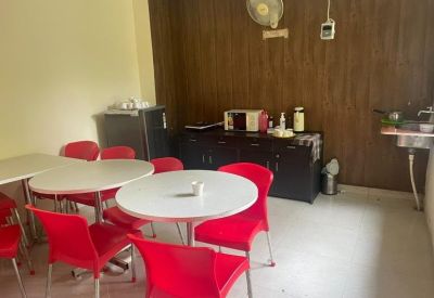 Communal kitchen and dining area with round white tables and vibrant red chairs.