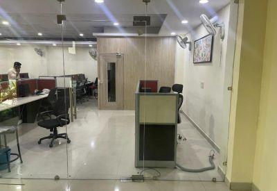 Reception area with glass partitions and a small desk leading to an open office.