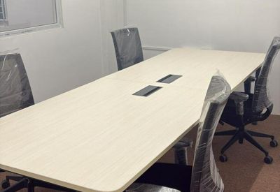 Bright four-person meeting room with a light wood table and wall-mounted air conditioning unit.