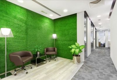Reception waiting area featuring a vibrant green grass-textured feature wall and plants.