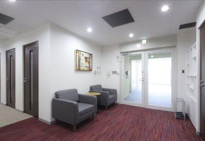 Lounge area featuring two grey armchairs, a small side table, and dark wood doors.