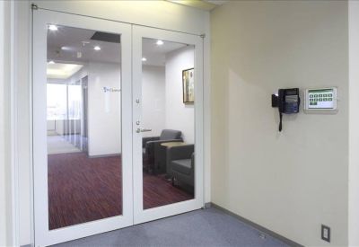 Secure office entrance with glass double doors, a telephone intercom, and red carpeting.