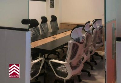 Modern conference room with high-back white chairs and wooden table.