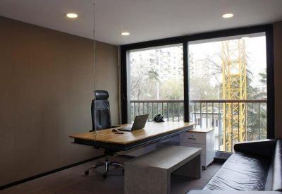 Private office suite with a wooden desk and a large window overlooking a construction crane.