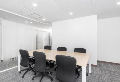 Meeting room with six black chairs around a light wood table.
