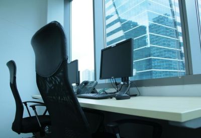 Modern office workspace with black ergonomic chairs and a large window overlooking city skyscrapers.