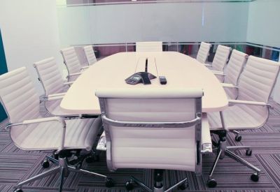 Bright conference room featuring a large white oval table and ergonomic white leather chairs.