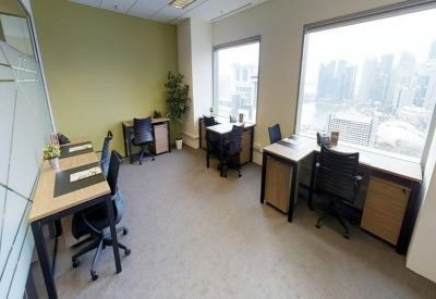 Shared office space with multiple workstations and large windows overlooking the city.