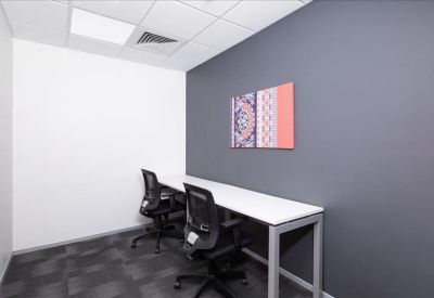 Private two-person office suite featuring a white desk, ergonomic chairs, and a colorful abstract wall art piece.