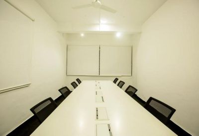 Minimalist boardroom with a long white table and black chairs.