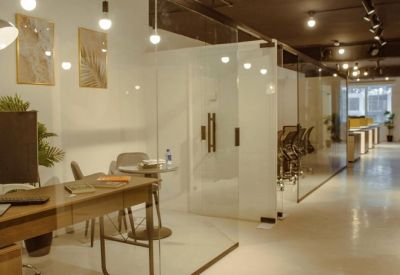 Modern glass-partitioned workspace with a central hallway and warm overhead lighting.