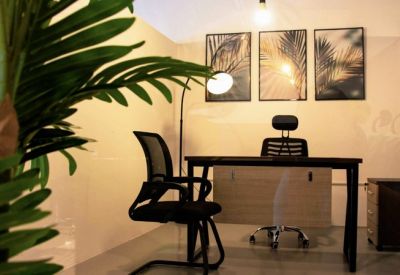 Private office suite with a wooden desk, mesh chair, and tropical leaf artwork.