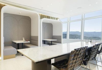 Bright breakout area featuring cozy individual booths and a large marble meeting table.