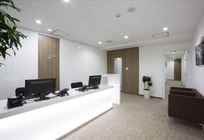Bright reception area with a white glowing front desk and comfortable seating.