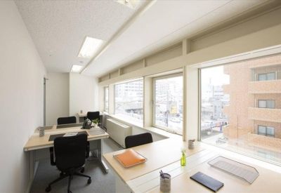 Bright office suite with multiple desks and large windows overlooking the city.