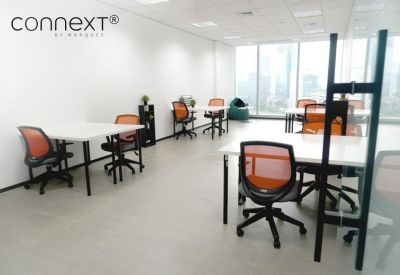 Spacious open-plan workspace with white desks and orange ergonomic chairs.