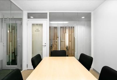 Private meeting room with a light wood table and glass wall partition.