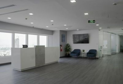 Spacious reception area with a minimalist white desk and blue velvet armchairs.