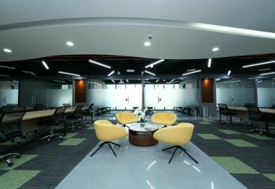 Modern lounge area with curved yellow armchairs and a circular coffee table on a polished floor.