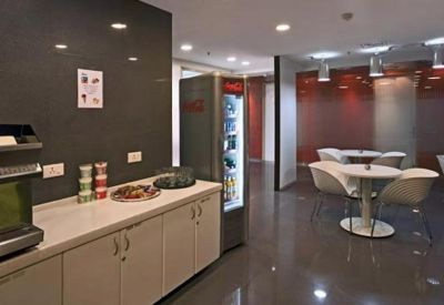 Communal breakout area with a refreshment counter, vending machine, and white dining sets.