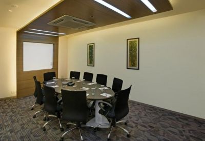 Professional meeting room with an oval table, black chairs, and wood-paneled ceiling features.