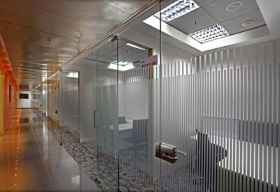 Modern corridor with glass-walled office suites and frosted privacy decals.